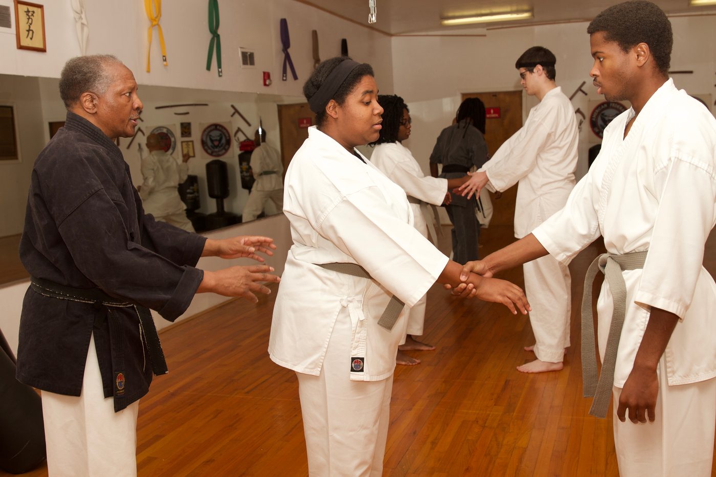 Ron J. Wiggins guiding students through a wrist-control technique on the dojo floor.